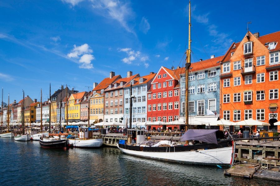 Photo des bâtiments colorés de Copenhague dans le port, avec petits voiliers amarrés le long du quai. 
