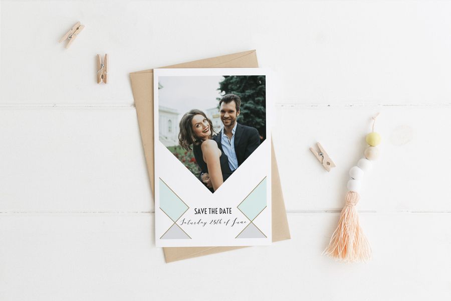 Une carte de mariage personnalisée Save-the-date avec photo devant un fond blanc avec des petites pinces à linge en bois de chaque côté.